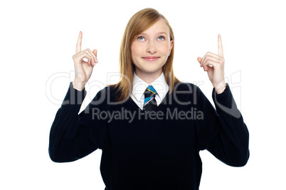 Amused schoolgirl looking and pointing upwards