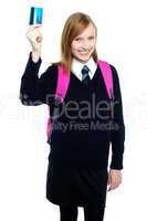 Teen girl in uniform holding up a cash card