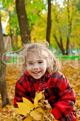Little girl with a bunch of yellow leaves