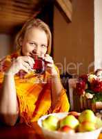 Young woman is drinking tea and smiling.