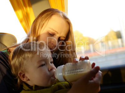 Mother is feeding her kid in the bus.