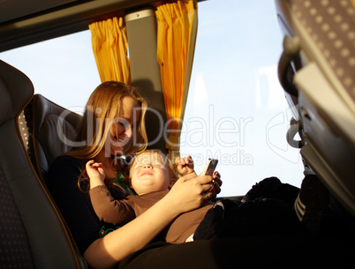Mother and kid are playing game on the phone.