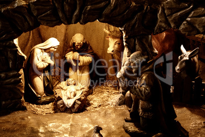 Nativity Scene. Made by wooden figures. Main characters are in the light spot.
