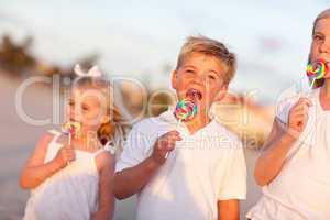 Cute Brother and Sisters Enjoying Their Lollipops Outside