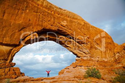 Woman staying with raised hands inside an Arch