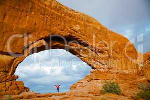 Woman staying with raised hands inside an Arch