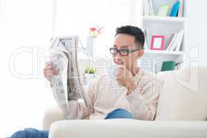 Asian drinking coffee and reading news paper