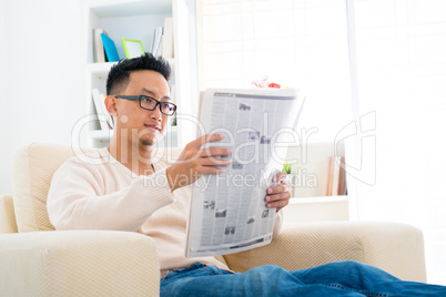 Southeast Asian male reading news paper