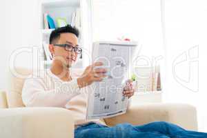 Southeast Asian male reading news paper