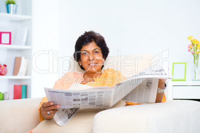Mature Indian woman reading news paper
