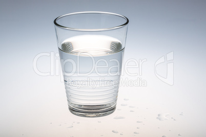 glass of water with some drops on the ground