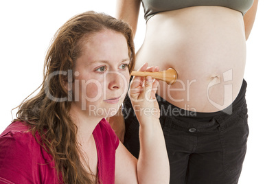 young midwife listening at pregnant human belly