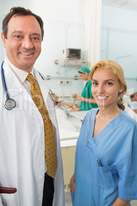 Smiling doctor and smiling nurse talking in a hospital ward