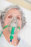 Elderly woman with an oxygen mask in a hospital