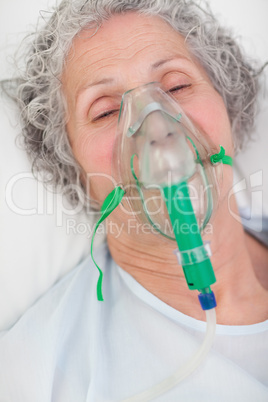 Elderly closing her eyes while lying in a hospital bed