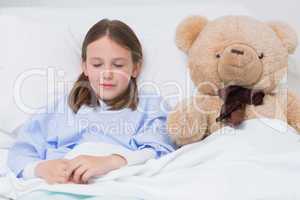 Child sleeping with a teddy bear while lying in a bed
