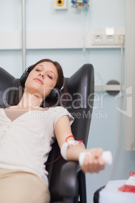 Female patient listening to music while giving her blood in a ho