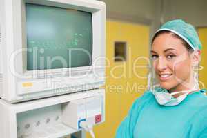 Smiling surgeon standing next to a monitor