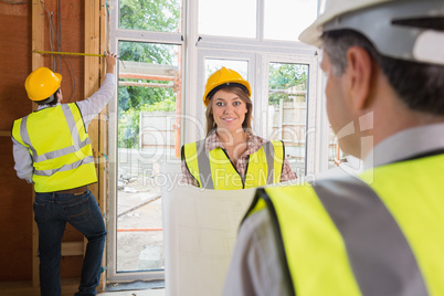Woman smiling at architect while man is measuring
