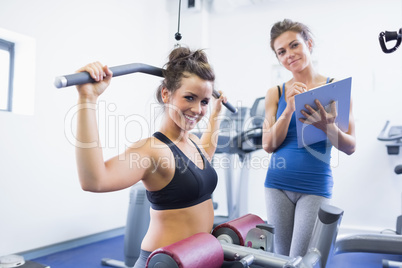 Smiling woman on weights machine with trainer