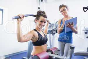 Smiling woman on weights machine with trainer