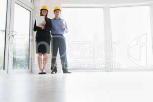 Man and woman holding clipboard and blueprint