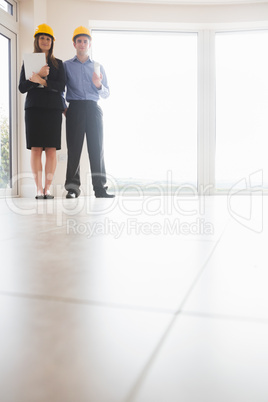 Woman and man holding blueprint and clipboard