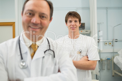 Smiling doctor and a male nurse folding their arms