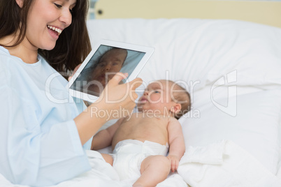 Mother using a tablet to take a picture of a newborn baby