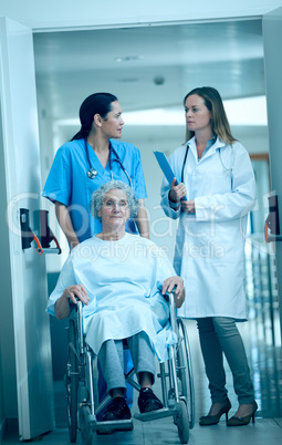 Nurse wheeling a senior patient patient in a hallway