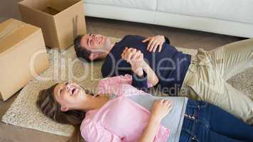 Laughing couple lying on floor with moving boxes