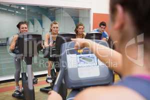 Instructor motivates happy people at spinning class