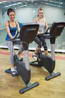 Two happy women on exercise bikes