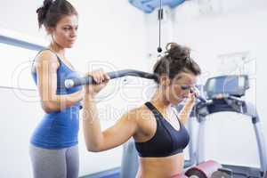 Woman using weights machine with female trainer