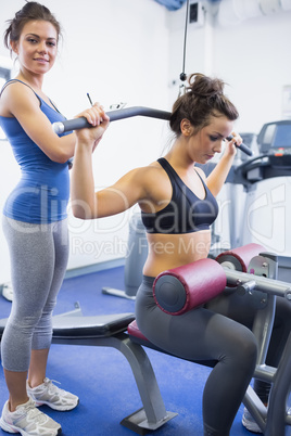 Female trainer with client on weights machine