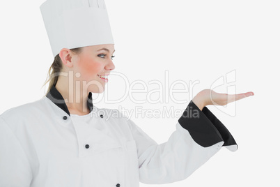 Happy female chef looking at invisible product