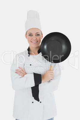 Female chef with arms crossed holds frying pan