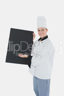 Female chef in uniform displaying black billboard