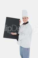 Female chef in uniform displaying black billboard