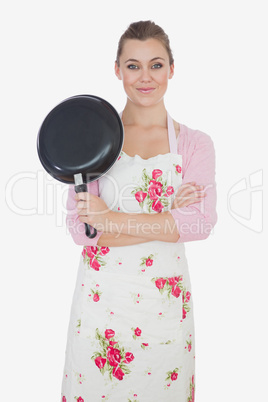 Young woman with arms crossed holding frying pan