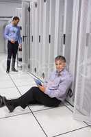 Smiling technician using tablet pc sitting on floor