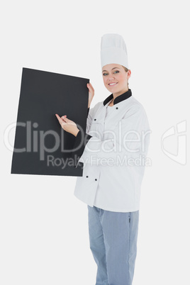 Female chef pointing on black billboard