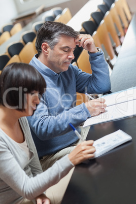 Man and woman taking notes during lecture