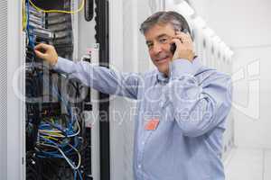 Man fixing server wires and talking on phone