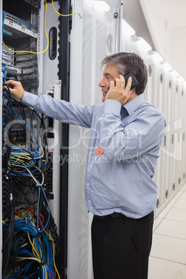 Man fixing wires while making a phone call