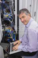 Man typing on laptop while doing server maintenance