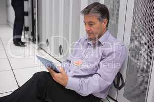 Man doing maintenance on tablet pc while sitting on the floor