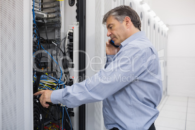 Technician phoning while repairing a server