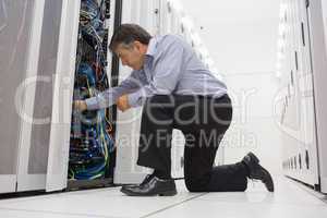 Technician kneeling and repairing a server with his hands