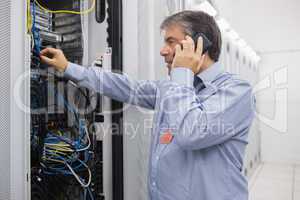 Technician phoning while repairing the server